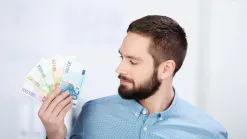Muž v modrej košeli drží vejár eurobankoviek – legálna spolupráca so živnostníkom