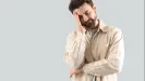 muž s rukou na tvári na sivom pozadí, štúdiový záber